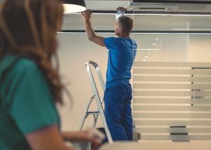 A man cleaning the ceiling of an office