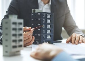 Two people examining a model of a tall building