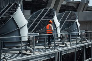 A worker inspecting HVAC equipment on the roof of a building